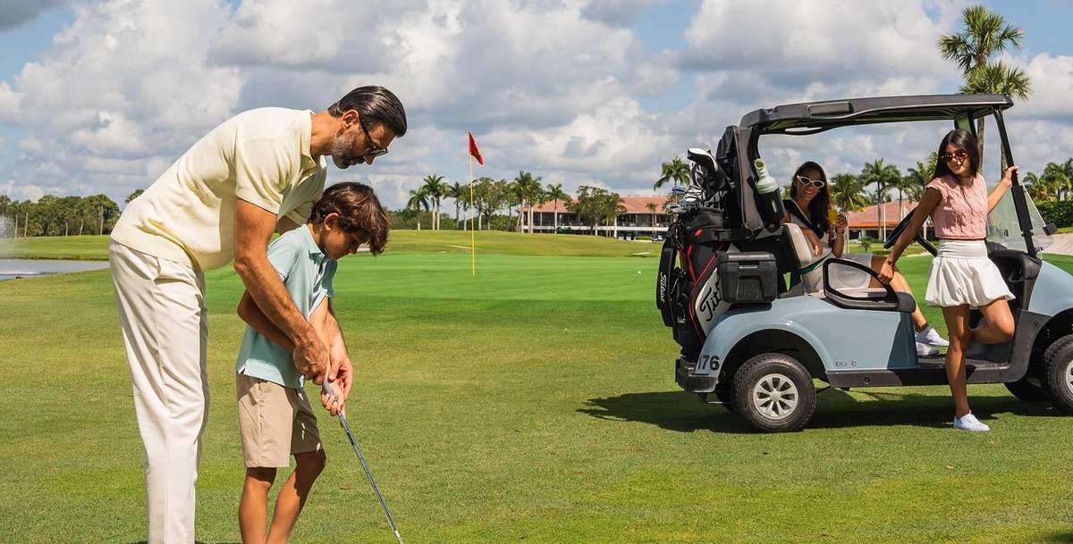 Golf pro demonstrating a smooth swing with a hybrid club to a student on the driving range