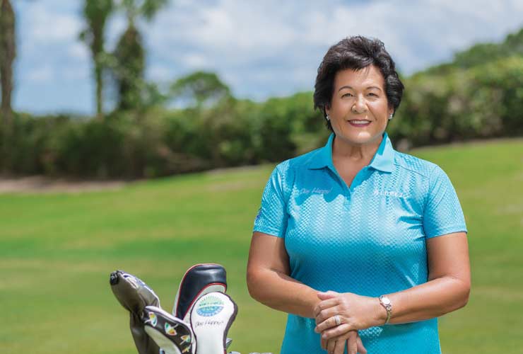 Nancy Lopez celebrating a tournament victory on the green with arms raised and supporters cheering