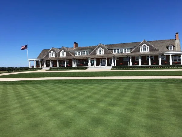 Long view down an Oakmont fairway showing narrow, austere lines framed by mature trees and tightly mown edges